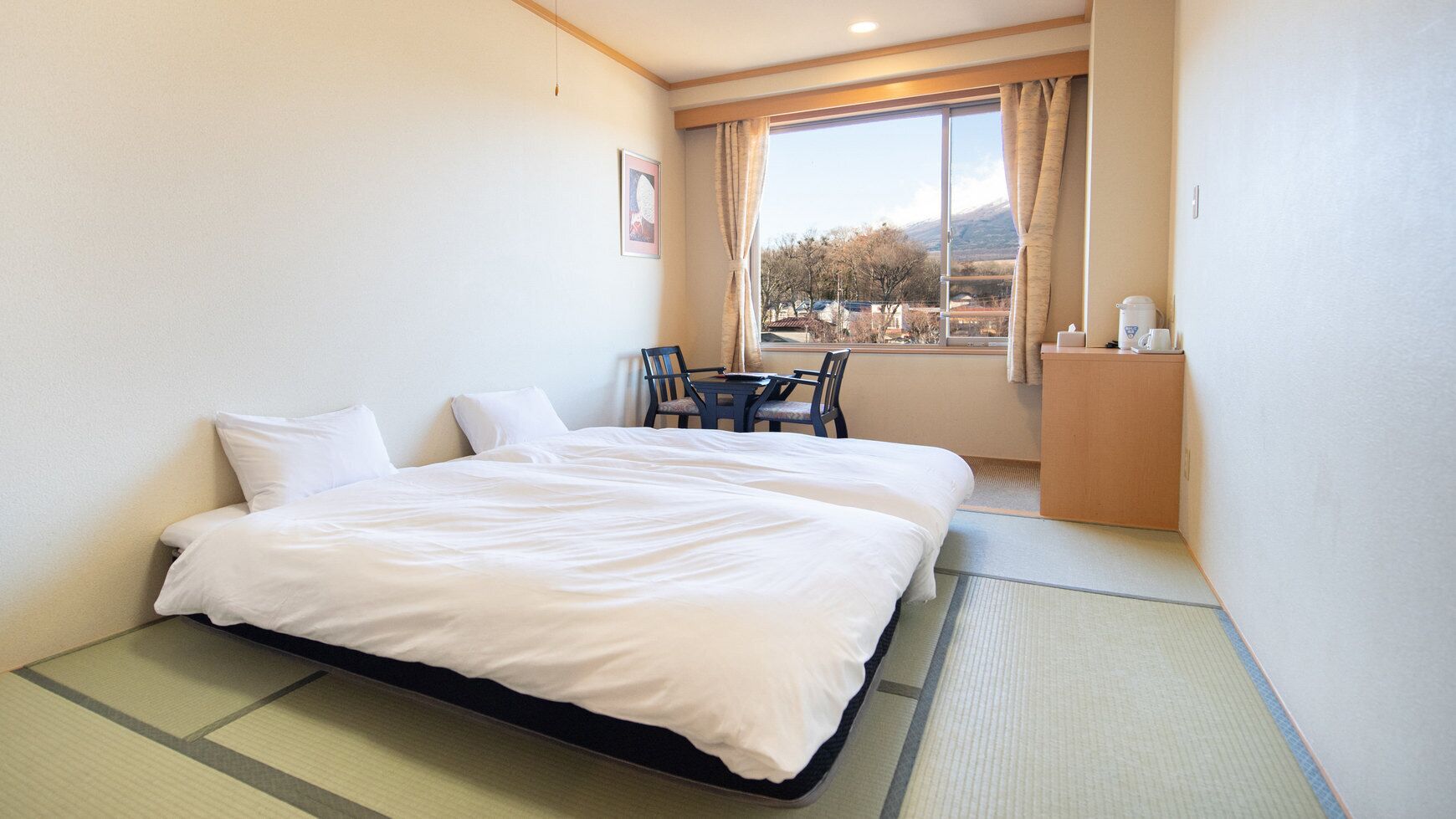 Een hotelkamer met een bed, een stoel, een tafeltje en een raam met uitzicht.