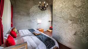 A bedroom with a large bed, red pillows, a chandelier, and a wall with floral patterns. - Farmland B&B (Sanxing)