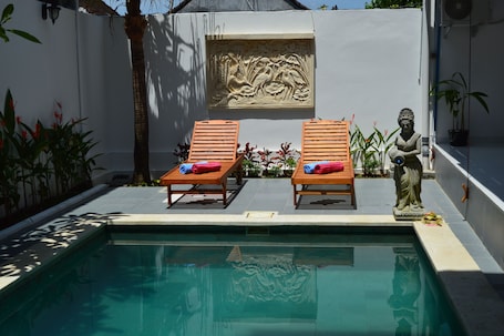 Una piscina al aire libre, sillones reclinables de piscina