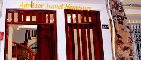 A building entrance with a sign reading "Advisor Travel Homestay."