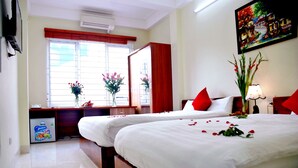 Une chambre d’hôtel avec deux lits, un bureau et une fenêtre avec des stores.