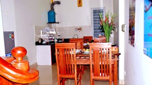 Un coin repas avec des chaises et une table en bois, une cuisine à l’arrière-plan et un escalier menant à un autre niveau.