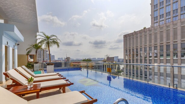 A rooftop pool with lounge chairs, a palm tree, and a cityscape view. - Huong Sen Annex Hotel (Ho Chi Minh City)