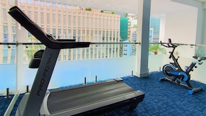 A gym with a ProForm treadmill and a stationary bike, carpeted floor, and large windows overlooking a building. - Huong Sen Annex Hotel (Ho Chi Minh City)