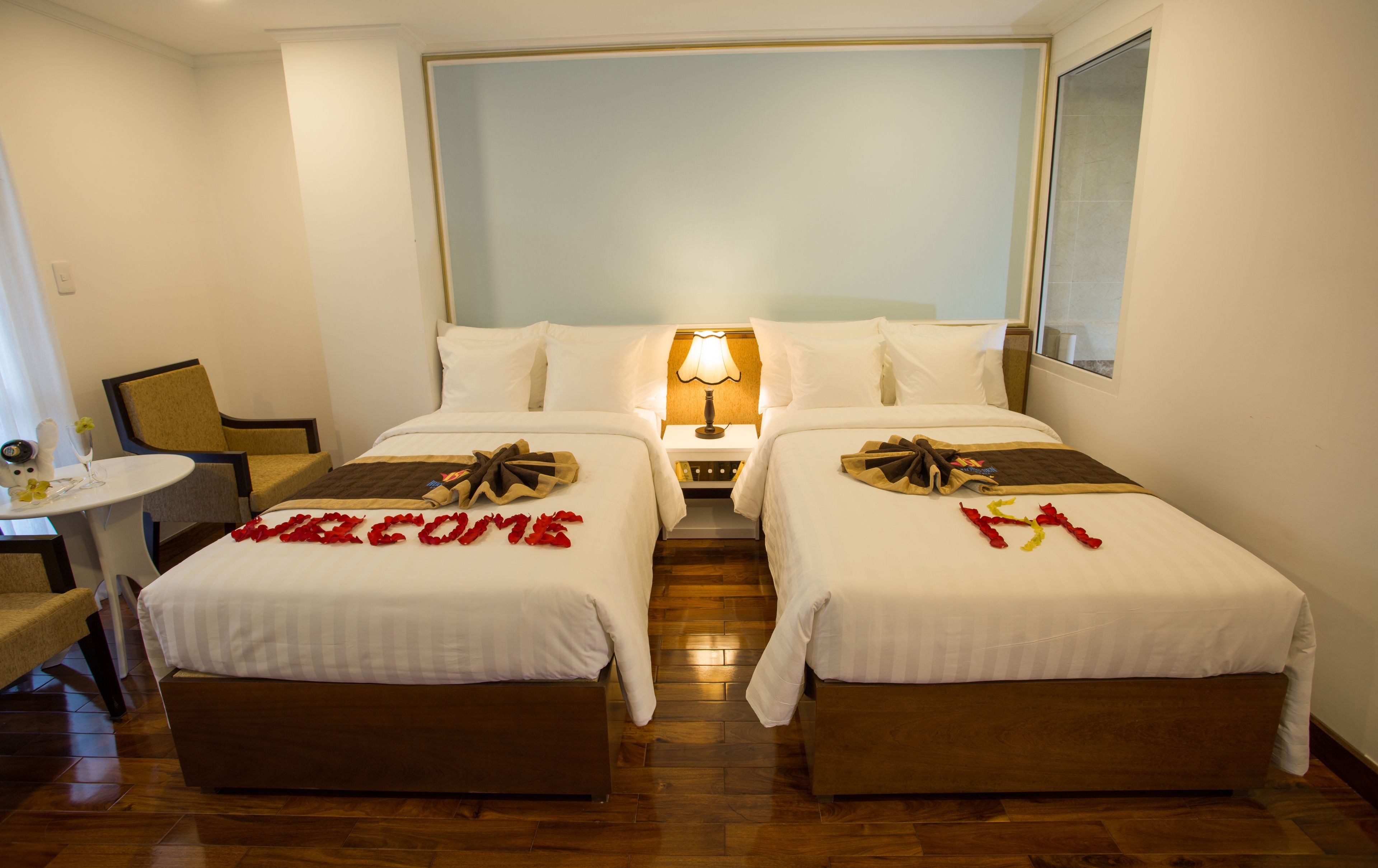 A hotel room with two beds, a small table, and a chair.