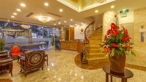 A hotel lobby with a reception desk, a staircase, and a large potted plant with red flowers. - Huong Sen Annex Hotel (Ho Chi Minh City)
