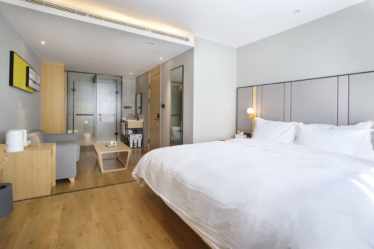 Een moderne hotelkamer met een groot bed, een bureau en een douchehoek.