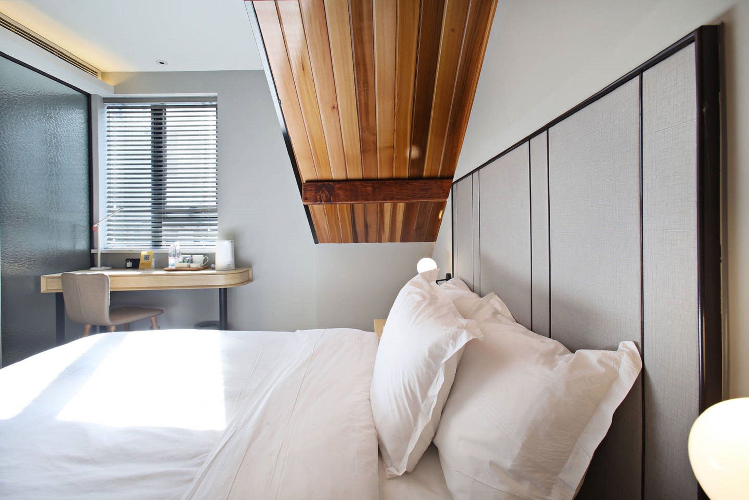 Una habitación de hotel moderna con una cama grande, un escritorio y vistas al exterior por la ventana.