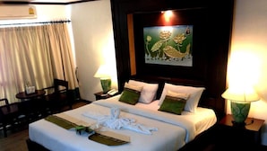 Una habitación de hotel con una cama bien hecha, un cuadro en la pared y dos lámparas de noche.