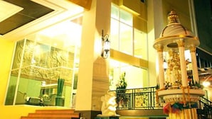Fachada de hotel con una escalera monumental, una fuente y un amplio ventanal.