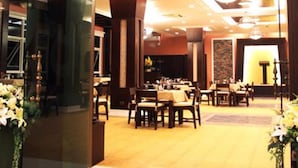 Entrada de un restaurante con letrero, mesas, sillas y piso alfombrado.