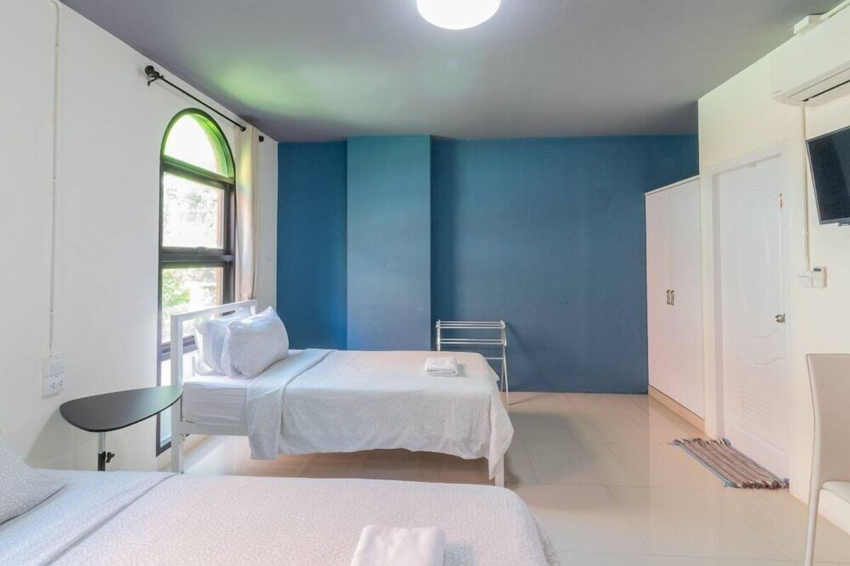 Quarto com duas camas, janela com vista, porta-toalhas e televisão na parede.