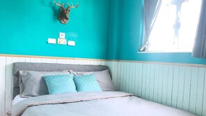 A bedroom with a teal wall, a mounted deer head, a bed with white bedding, and a window with curtains. - Mingdu Hostel (Kowloon)