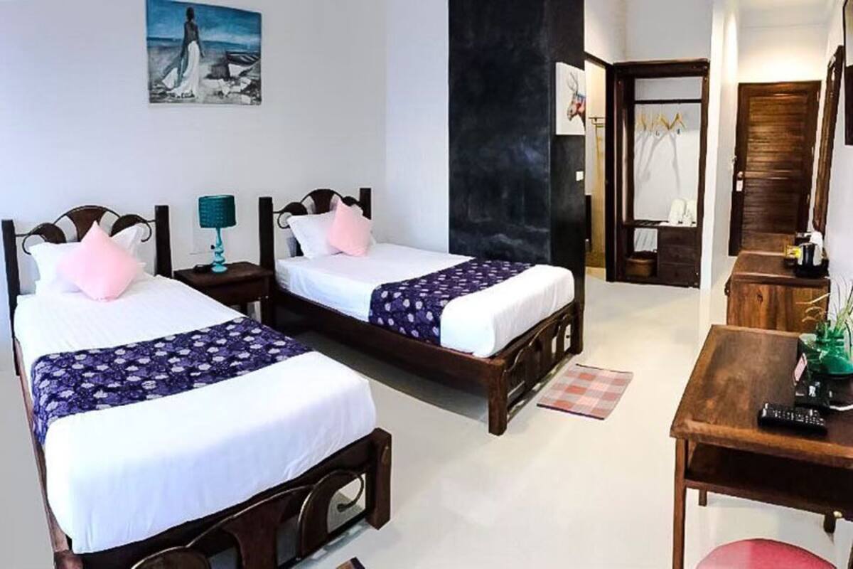 Ein Hotelzimmer mit zwei Betten, einem Holztisch, einem Spiegel und einem Bild an der Wand.