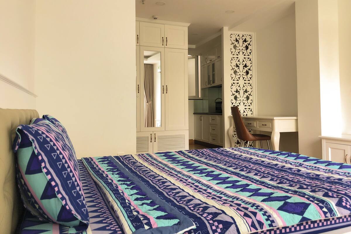 Um quarto com cama, escrivaninha e guarda-roupa.