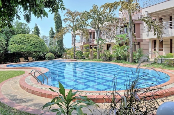 A swimming pool with a checkered pattern, surrounded by a brick border and greenery.