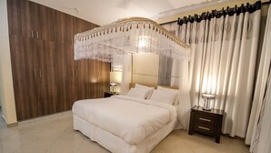 Un dormitorio con una cama grande, una mesita de noche, un armario y una cama con dosel.