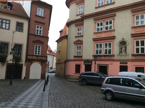 A cobblestone street lined with historic buildings, including a restaurant and a vintage shop. - Proko 2 (Prague)