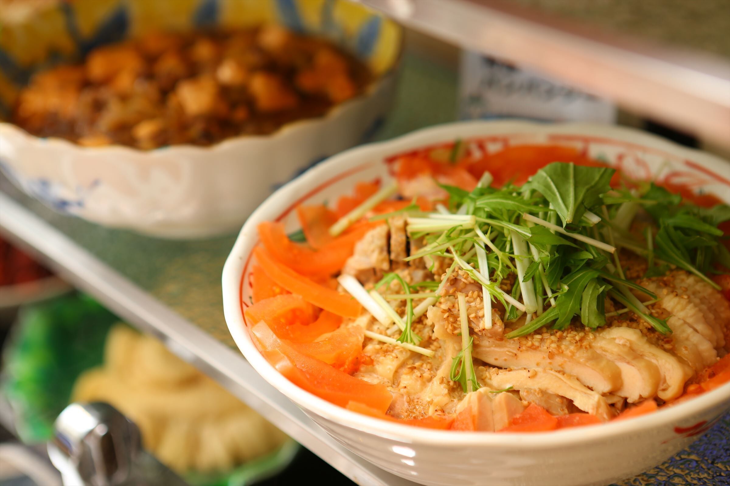 A bowl of food with shredded carrots and greens, possibly a salad or soup.