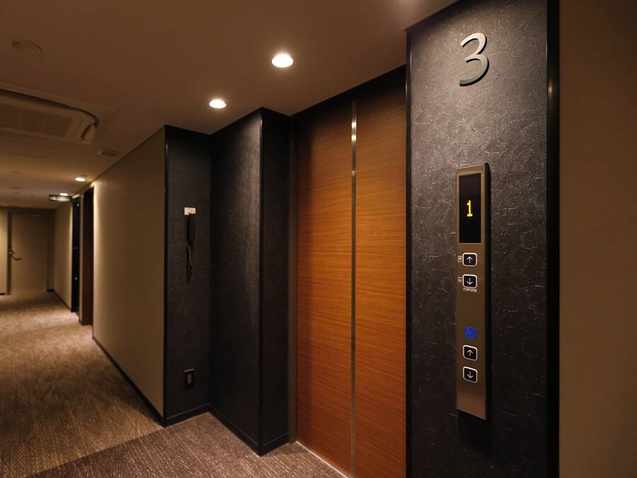 Un passadís d'hotel amb un ascensor i una porta amb el número 3.