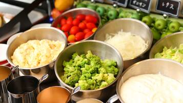 A variety of food items in metal bowls, including broccoli, tomatoes, and other vegetables.