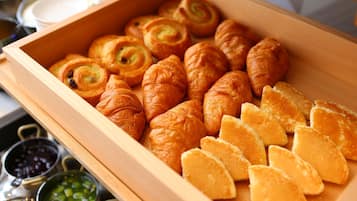 A wooden box containing various pastries and sliced bread.