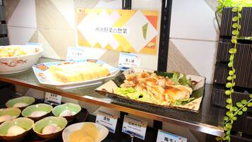 Un buffet proposant divers plats, notamment des prunes marinées et un plat à base de poulet.