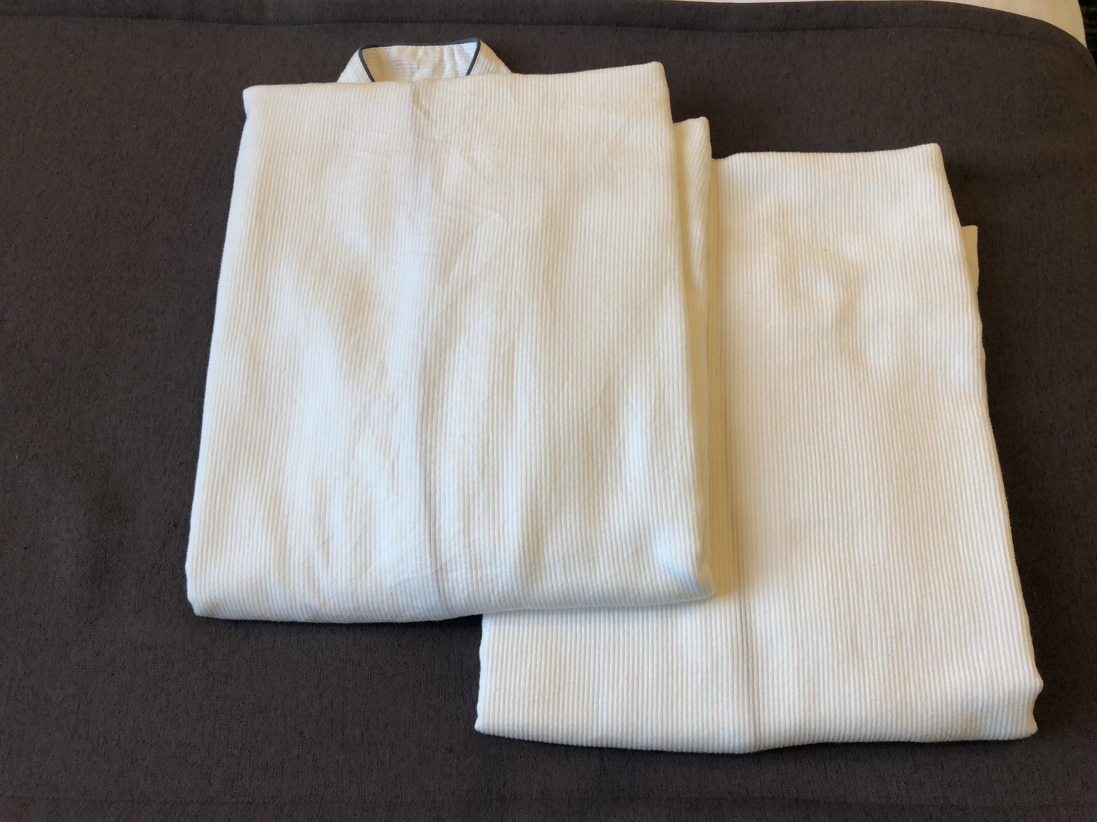 Two folded white towels on a dark-colored sofa.