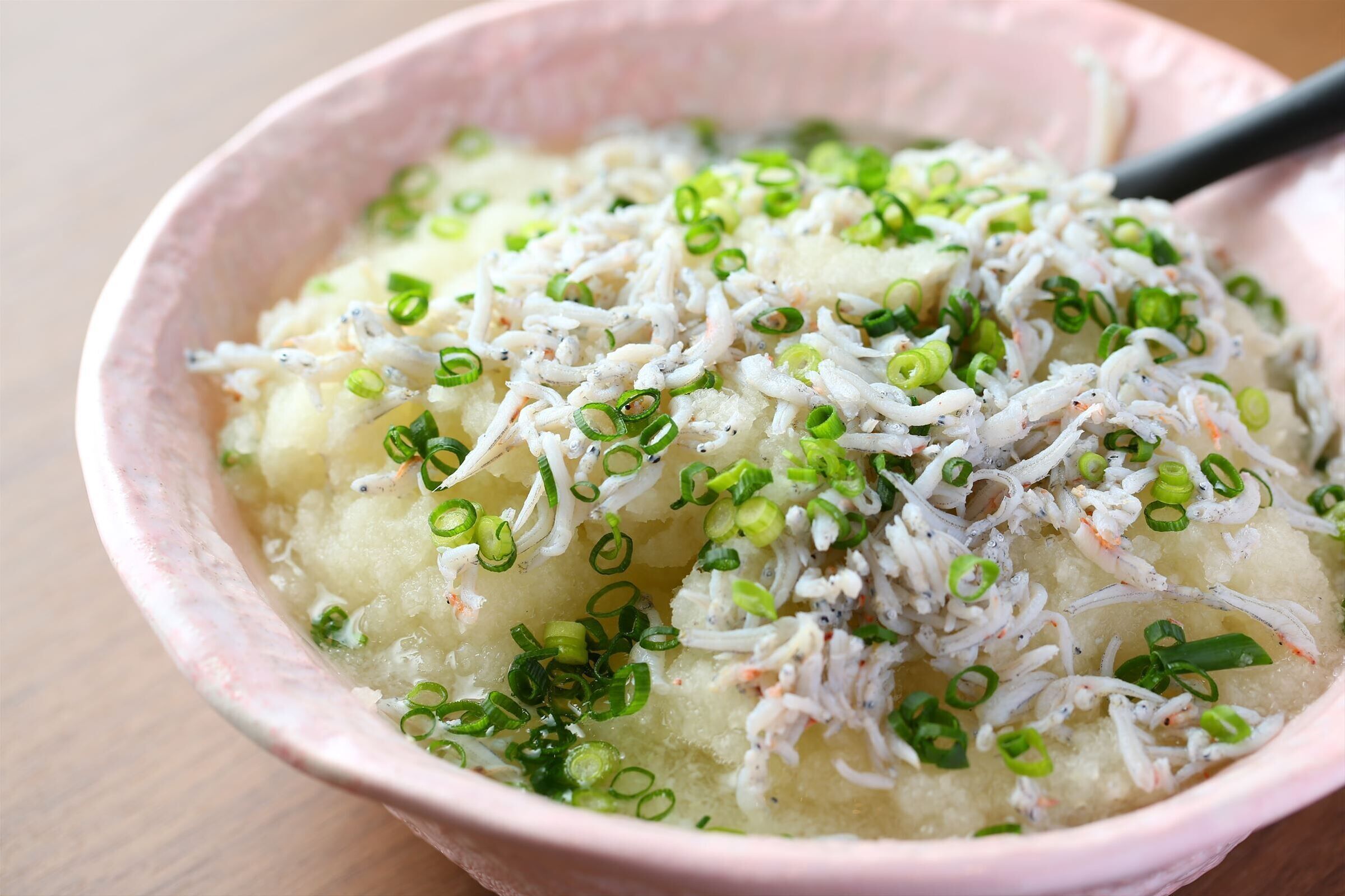 A bowl of food with shredded ingredients and green onions.