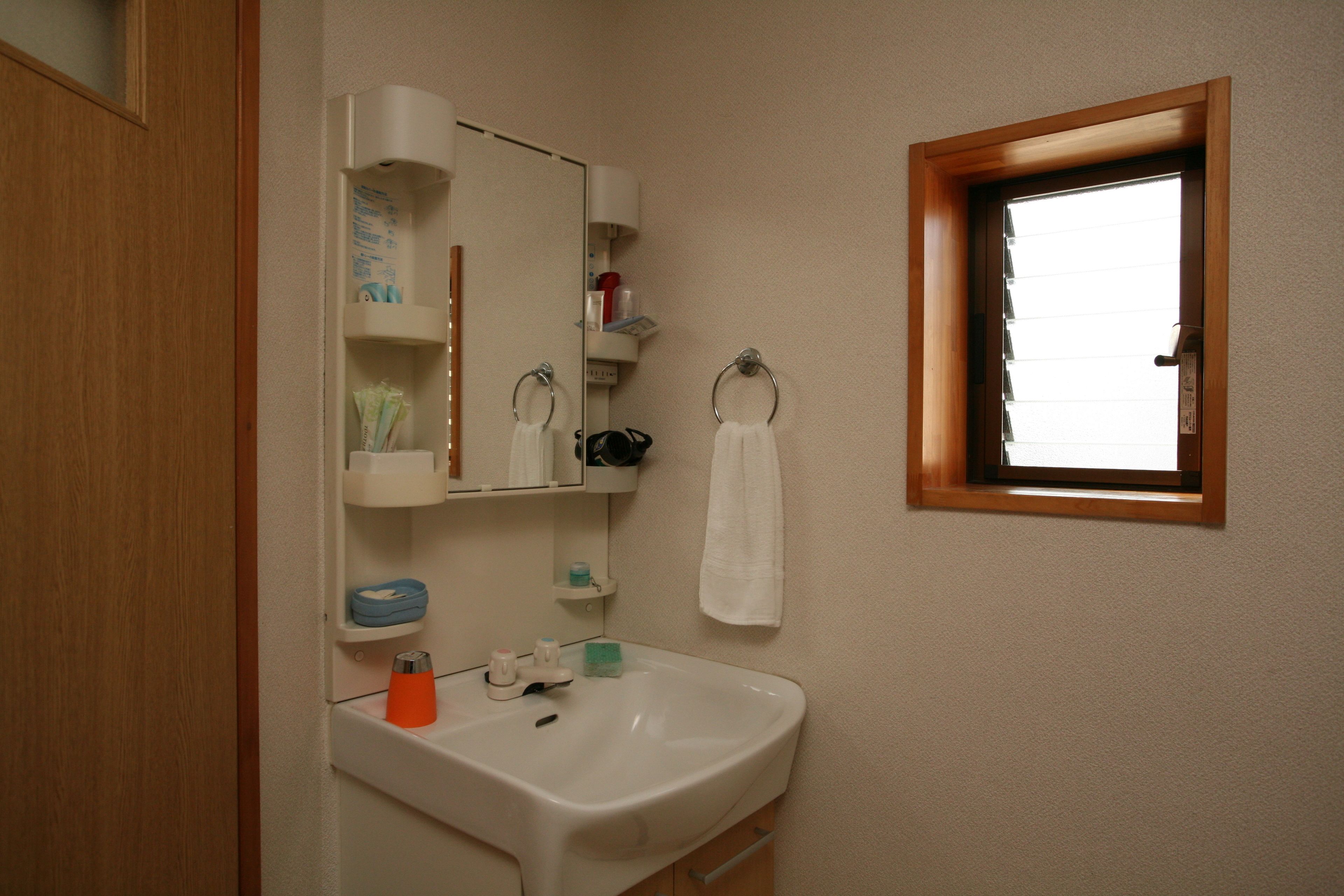 Un baño con lavamanos, espejo y ventana.