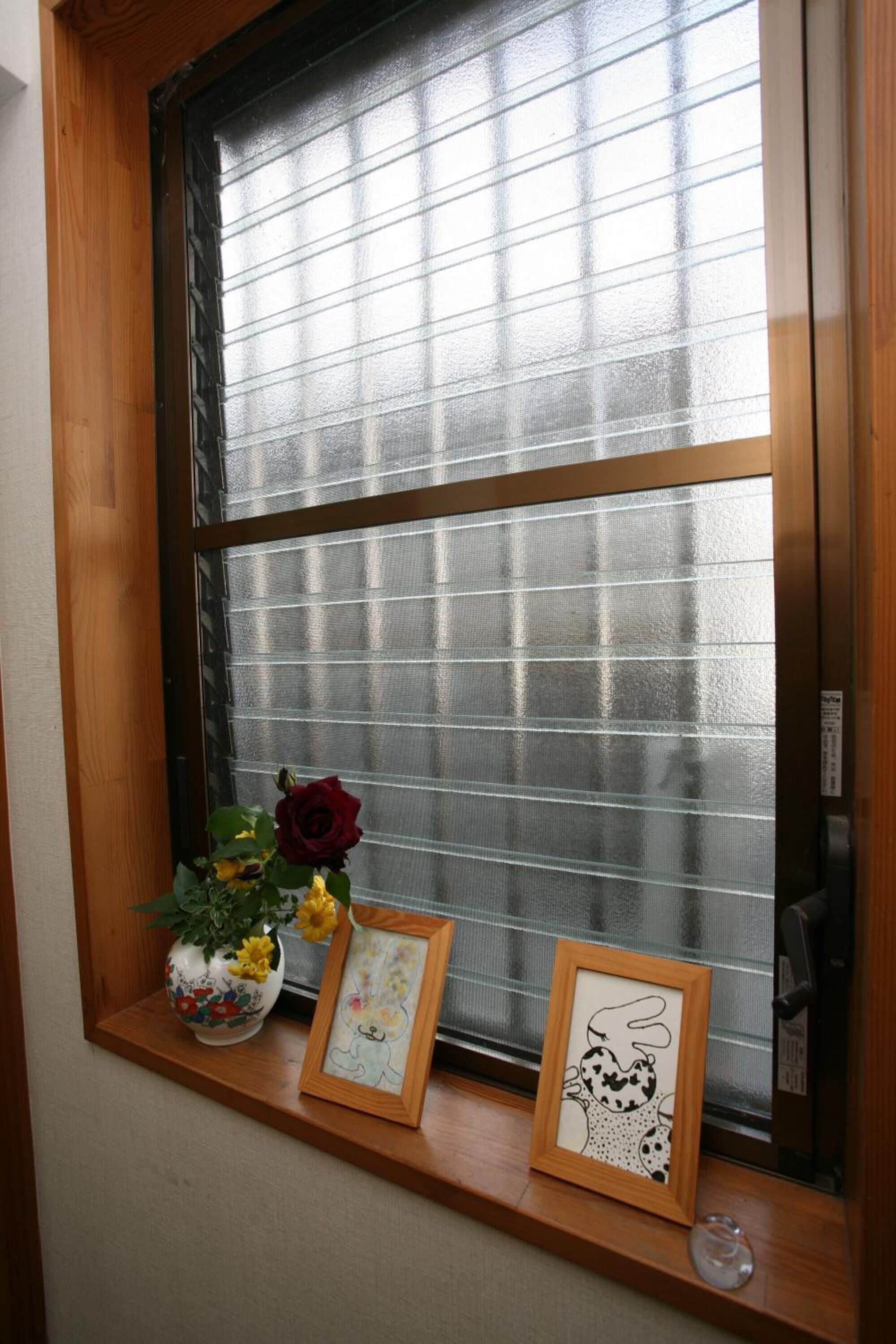 Una ventana con marco de madera, un panel de vidrio esmerilado y un estante debajo.