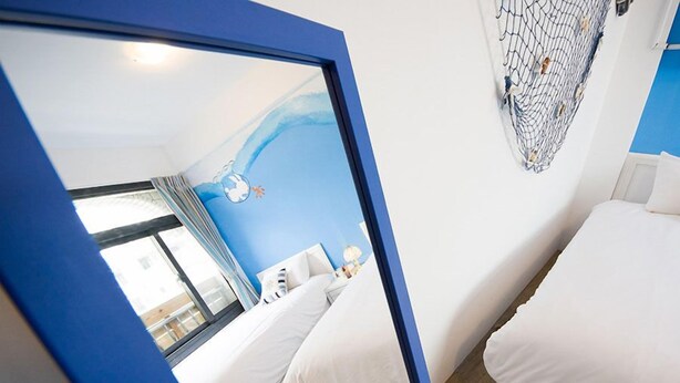 A bedroom with two beds, a blue wall, and a window. - E-Phone hotel (Ji'an)