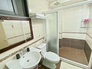Ein Badezimmer mit Waschbecken, Toilette und einer Duschkabine aus Glas.
