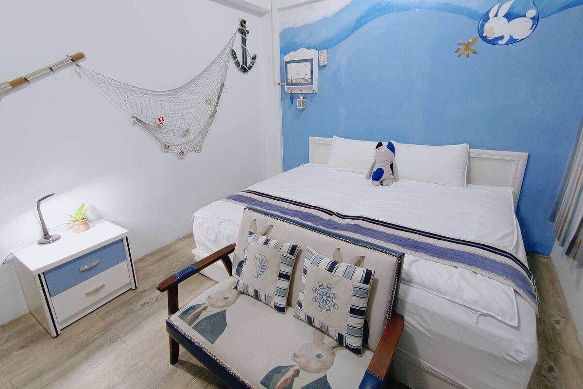 A bedroom with a bed, a desk, a chair, and a hammock.
