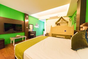 Ein Hotelzimmer mit einem Bett, einem Schreibtisch, einem Sessel, einem Fernseher und einer grünen Wand.