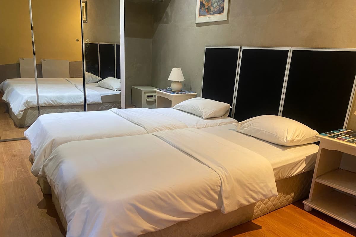 Ein Hotelzimmer mit zwei Betten, einem Nachttisch mit Lampe und einem weiteren kleinen Nachttisch mit Telefon sowie einem Spiegel.