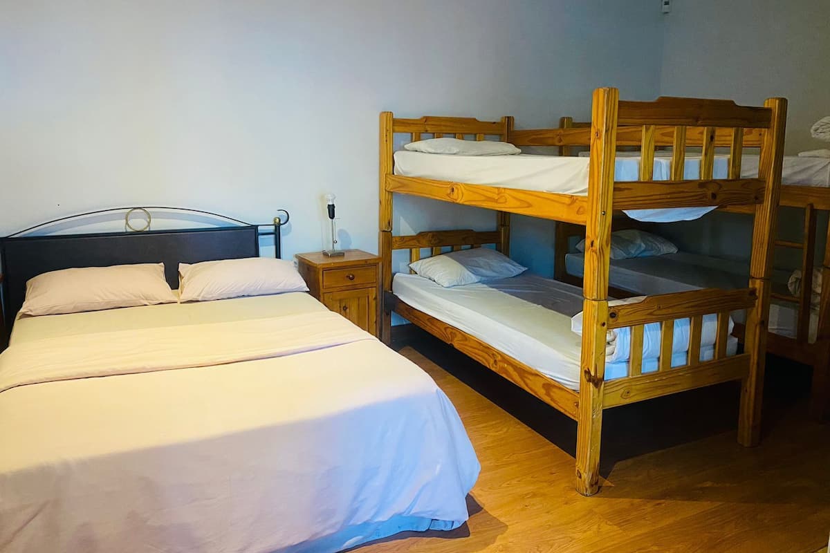 Eine Etagenbettanlage mit zwei Schlafstellen, einem Einzelbett und einem Nachttisch mit Lampe.