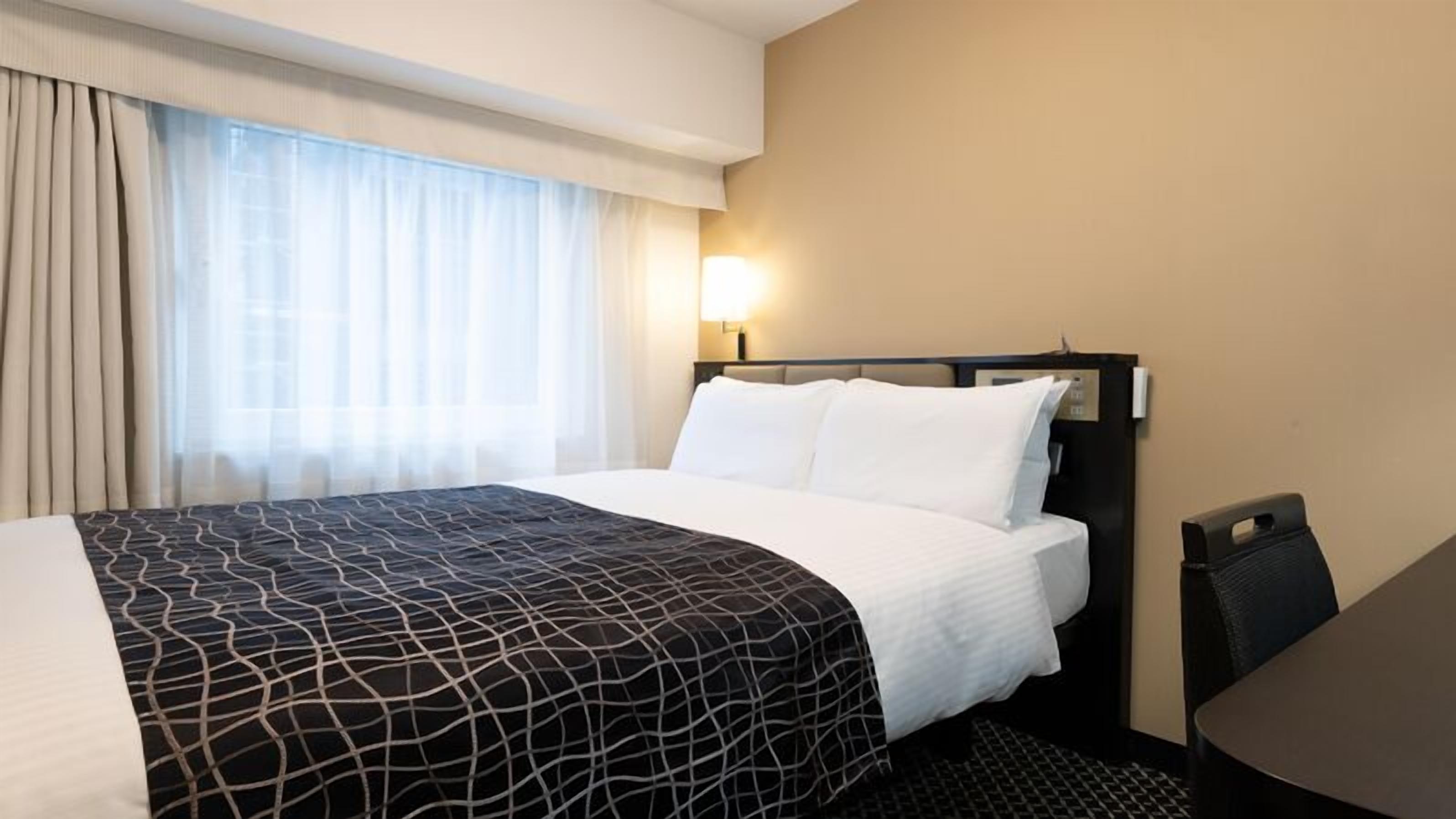 Ein Hotelzimmer mit Bett, Schreibtisch und Stuhl.