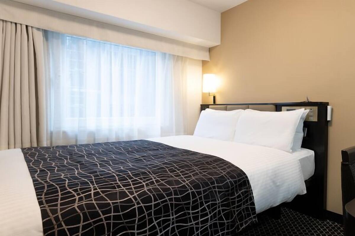 A hotel room with a bed, a desk, and a chair.