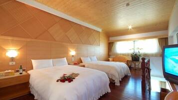 A hotel room with two beds, wooden ceiling, and a television.