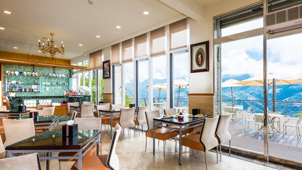 Un restaurante con vistas a montañas, que cuenta con una zona de bar, mesas y sillas para comer.