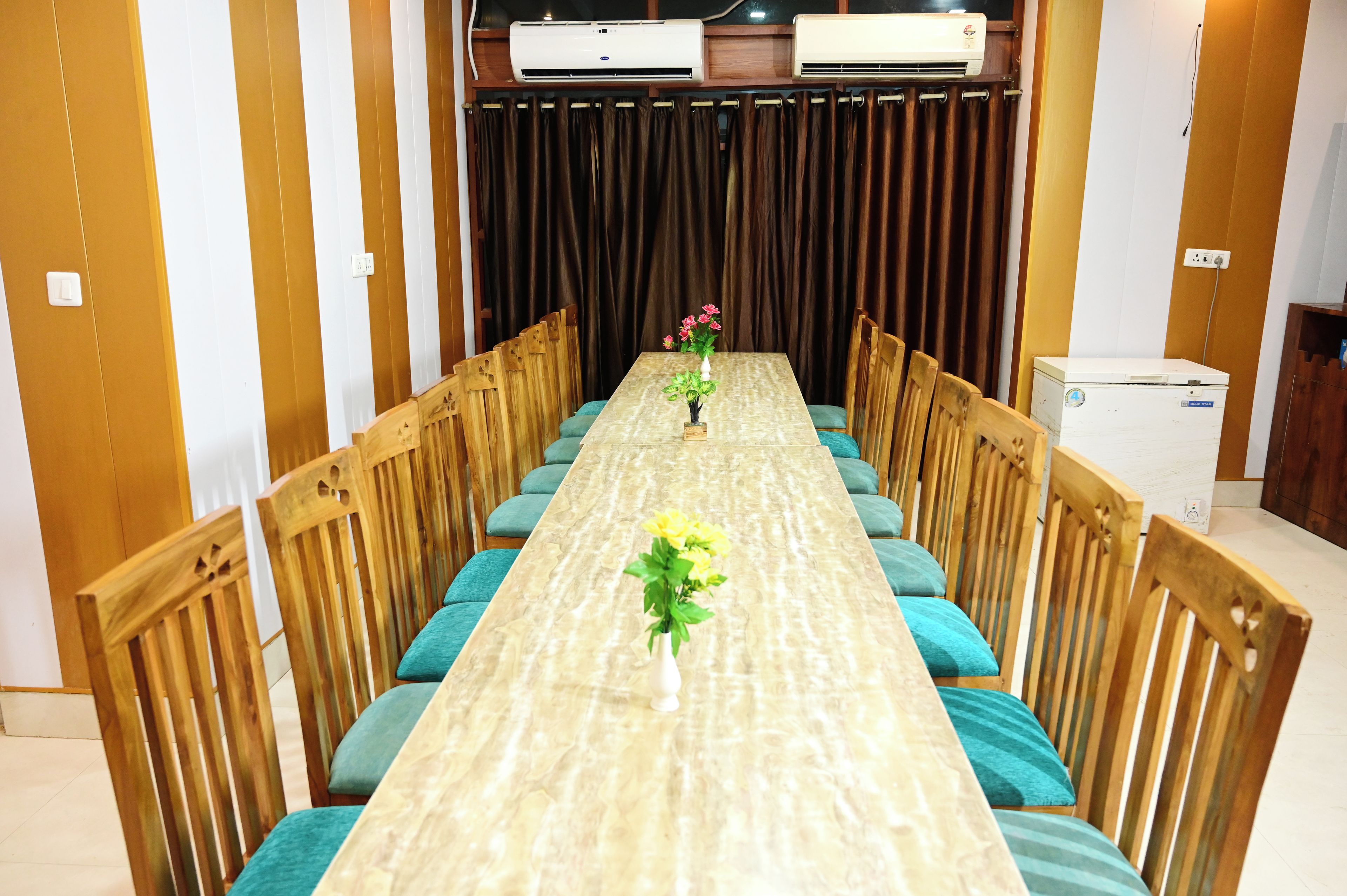 Una habitación con una larga mesa, sillas de madera y un telón de fondo.