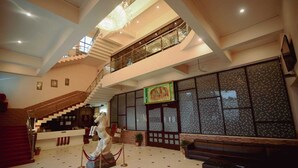 Un lobby espacioso con una imponente escalera, una estatua y una zona de recepción.