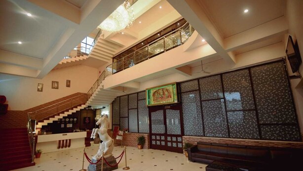Un lobby espacioso con una imponente escalera, una estatua y una zona de recepción.