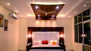 Un dormitorio moderno con una cama grande, ventilador de techo, iluminación empotrada y un amplio ventanal.