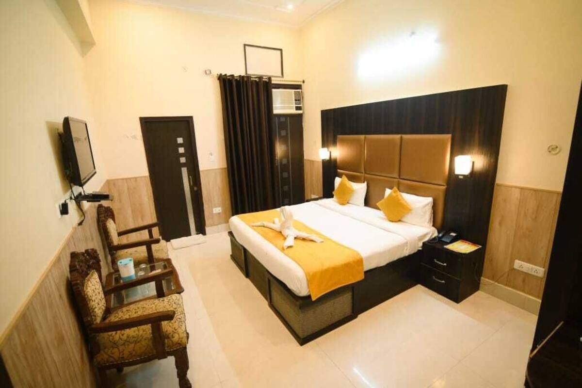 Quarto de hotel com cama, televisão, escrivaninha e cadeira.