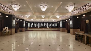 Um salão amplo com piso lustroso, luminárias decorativas no teto e um palco central.