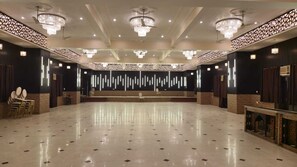 Une vaste salle dotée d’un plancher ciré, de luminaires décoratifs au plafond et d’une scène centrale.