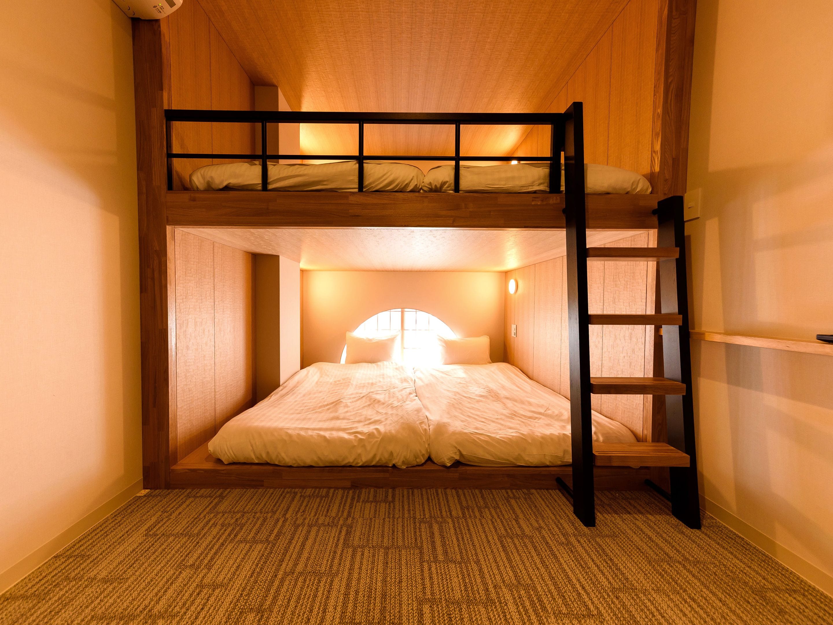 A bunk bed room with a wooden ceiling and a ladder.