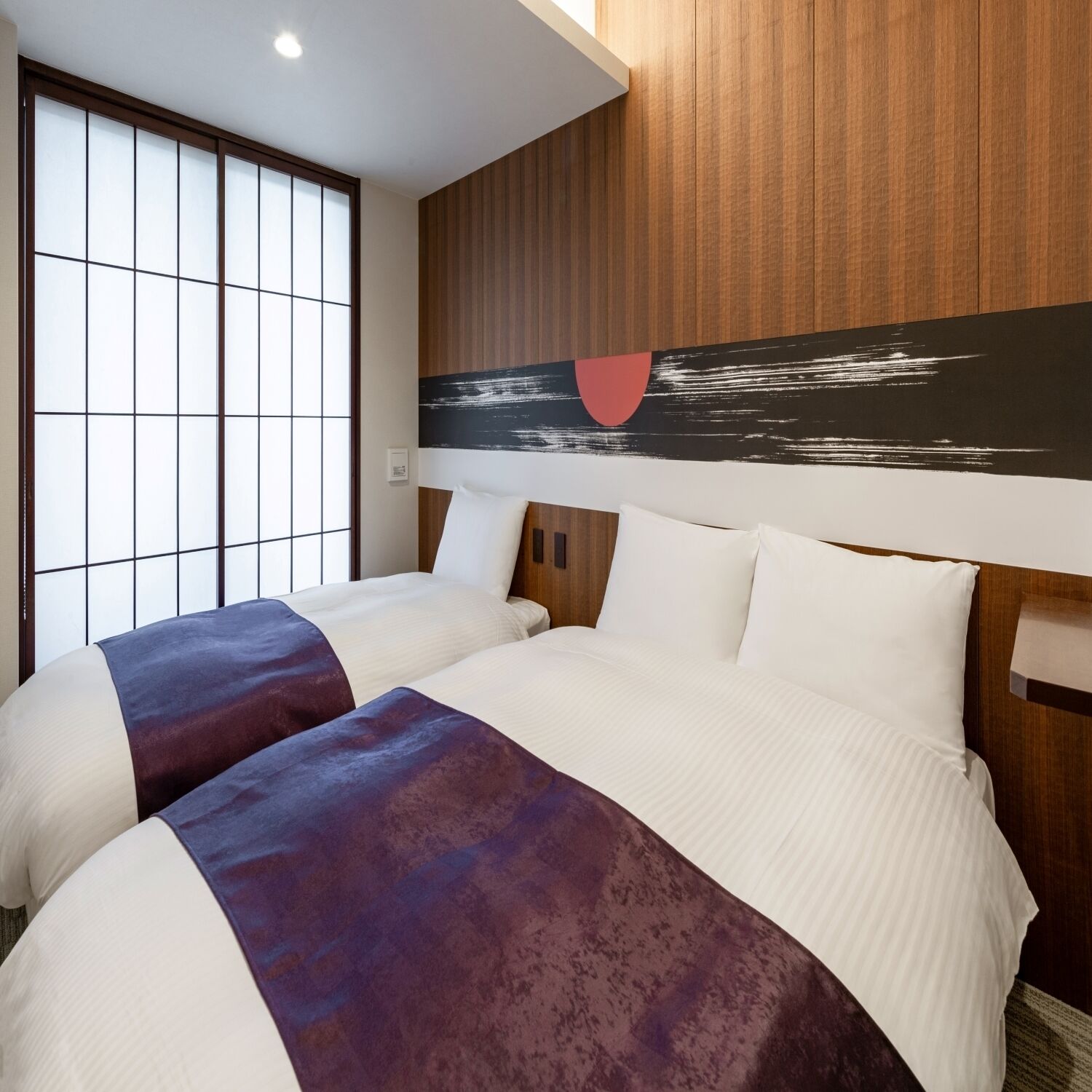 Habitación de hotel con dos camas, un ventanal con vistas y una obra de arte colgada en la pared.